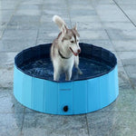 Dog playing in a blue portable dog pool on a tiled floor
